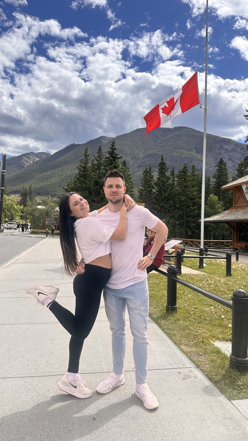 Couple portrait with a Canadian flag and mountains in Banff