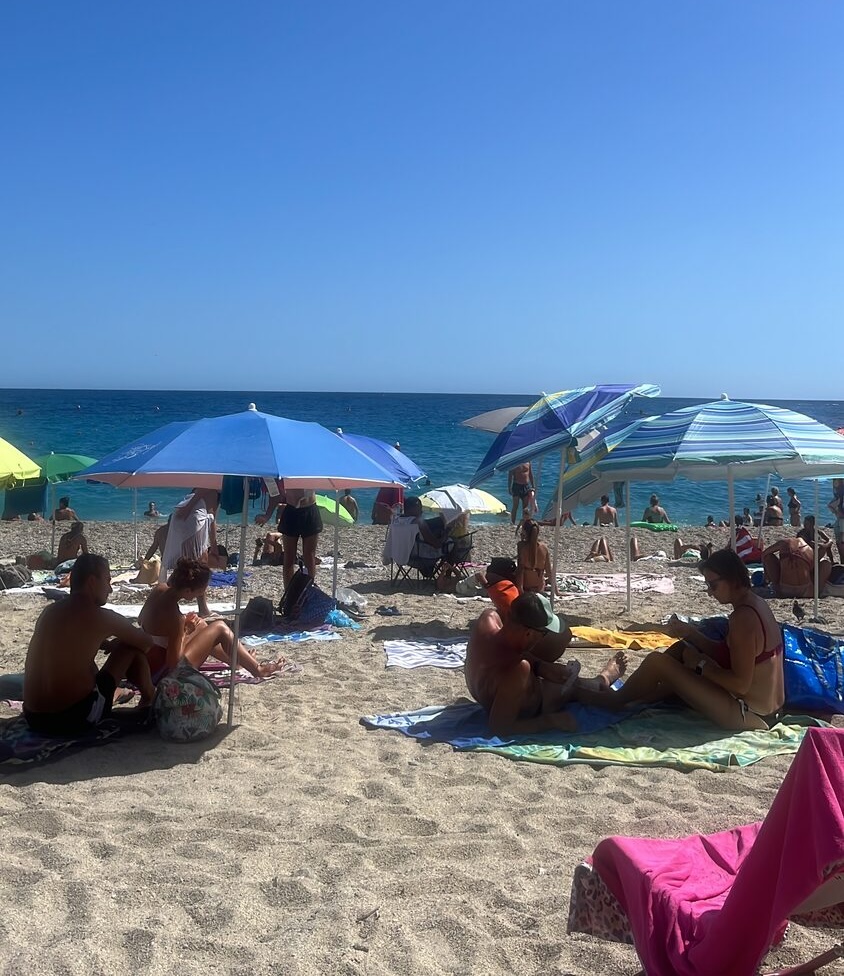 A busy Ligurian beach under a clear blue sky