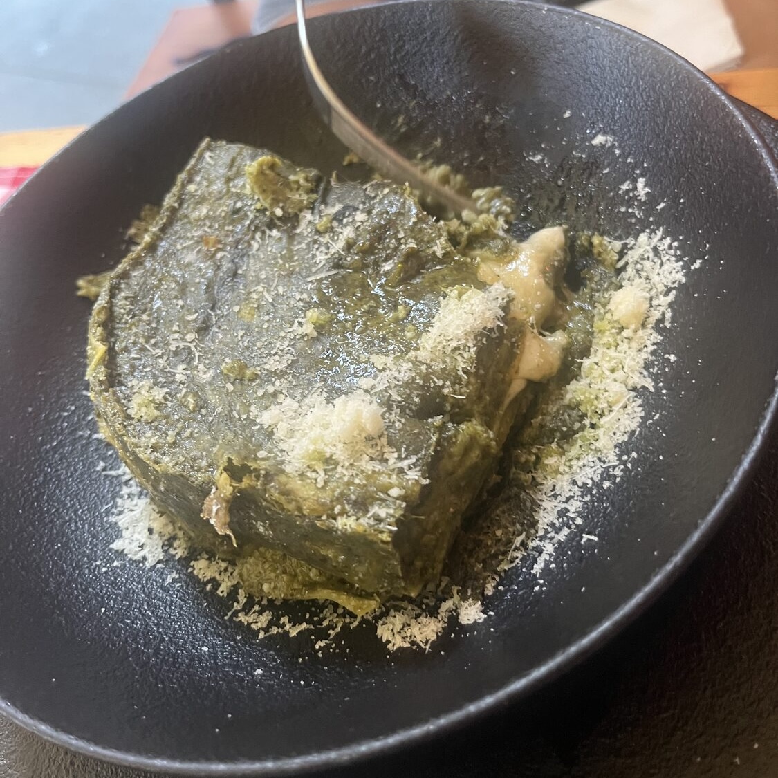 Pesto lasagna topped with grated cheese in Monterosso