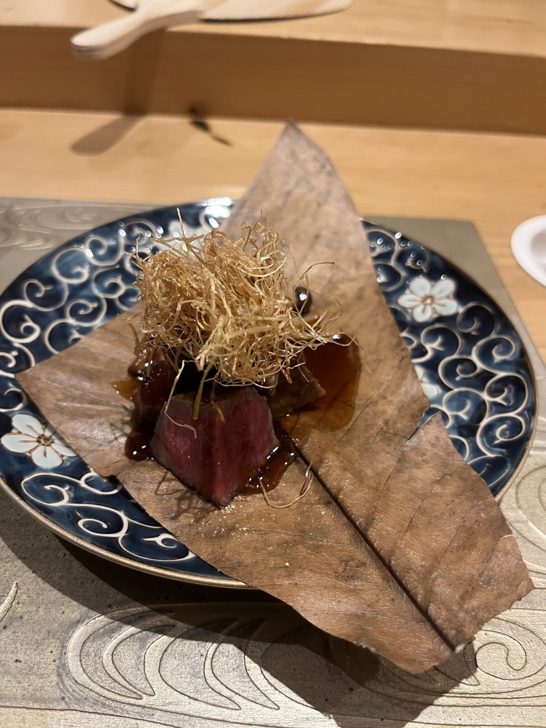 Beef wrapped in a dried leaf with crispy garnish